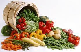 Assorted fresh vegetables spilling from a basket, including peppers, lettuce, potatoes, and carrots.