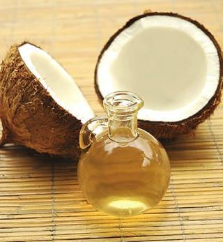 Coconut oil in glass jar with halved coconut on bamboo mat, healthy natural supplement