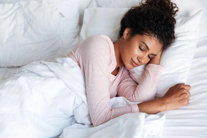 Woman sleeping peacefully in bed, promoting restful sleep and optimal health