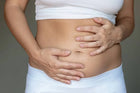 Woman holding bloated stomach, gut health and digestive wellness concept