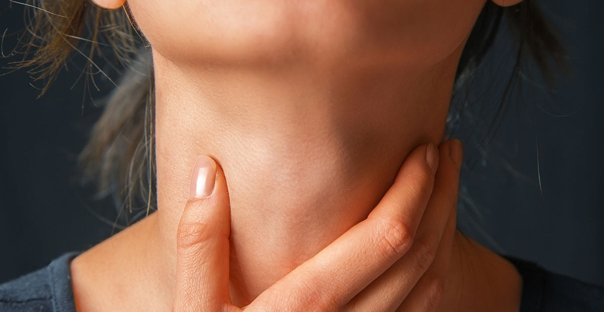 Close-up of a woman touching her throat, thyroid health concept