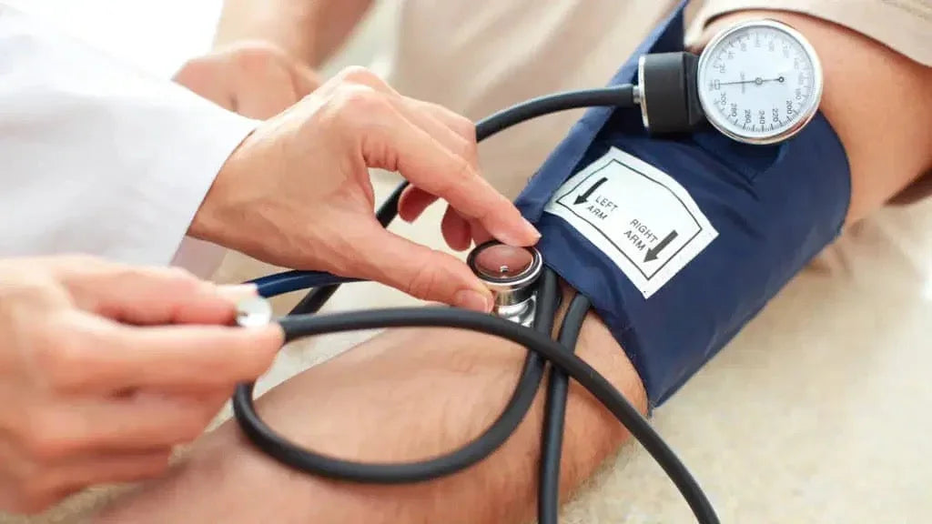 Doctor measuring blood pressure with stethoscope and cuff on patient's arm in clinic
