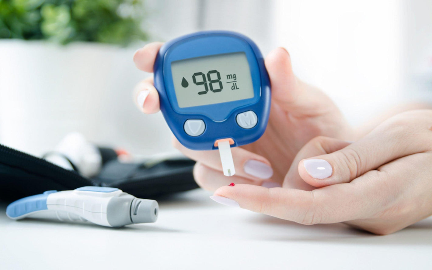 Person using blood glucose monitor with lancet for blood sugar testing
